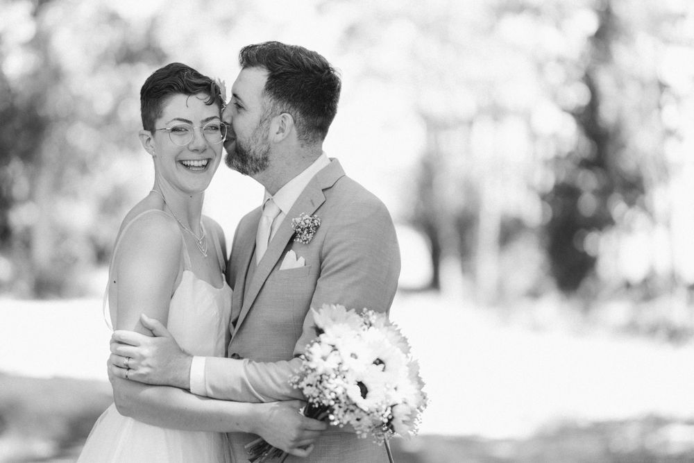 A black and white portrait captures an intimate wedding moment with soft natural lighting.