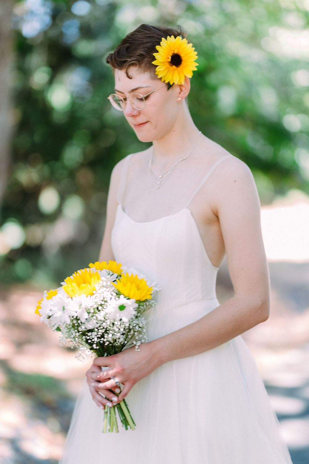A dreamy bridal portrait with a sunflower accent and classic white dress in natural lighting.