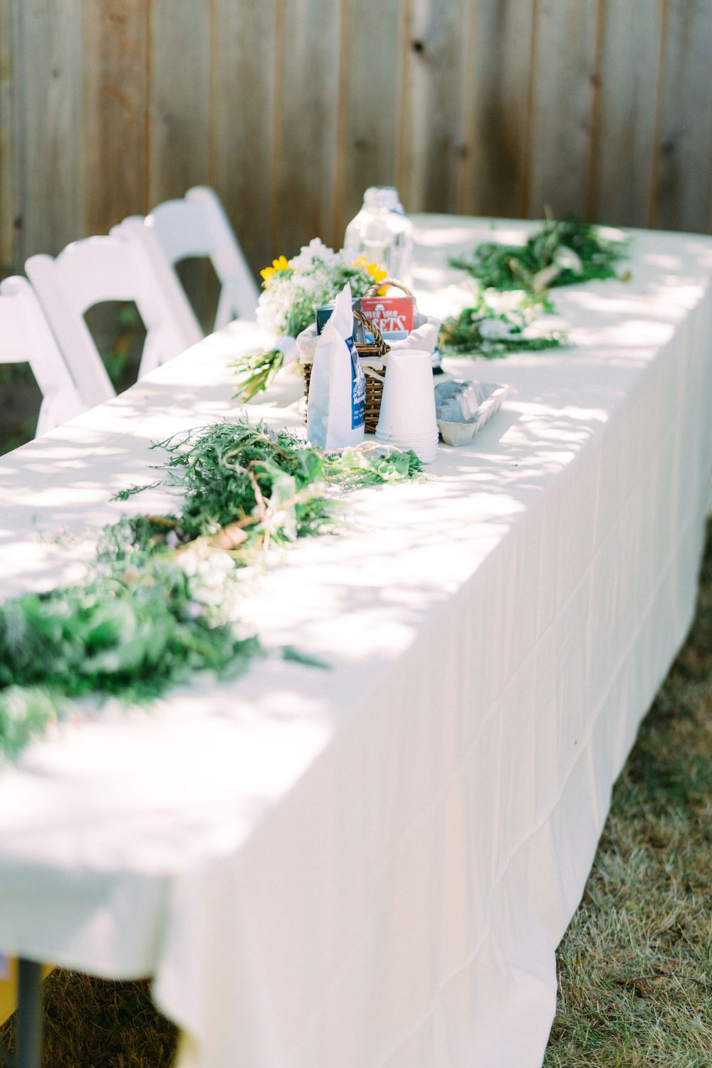 Elegant outdoor wedding table setup with white tablecloth and greenery decorations.