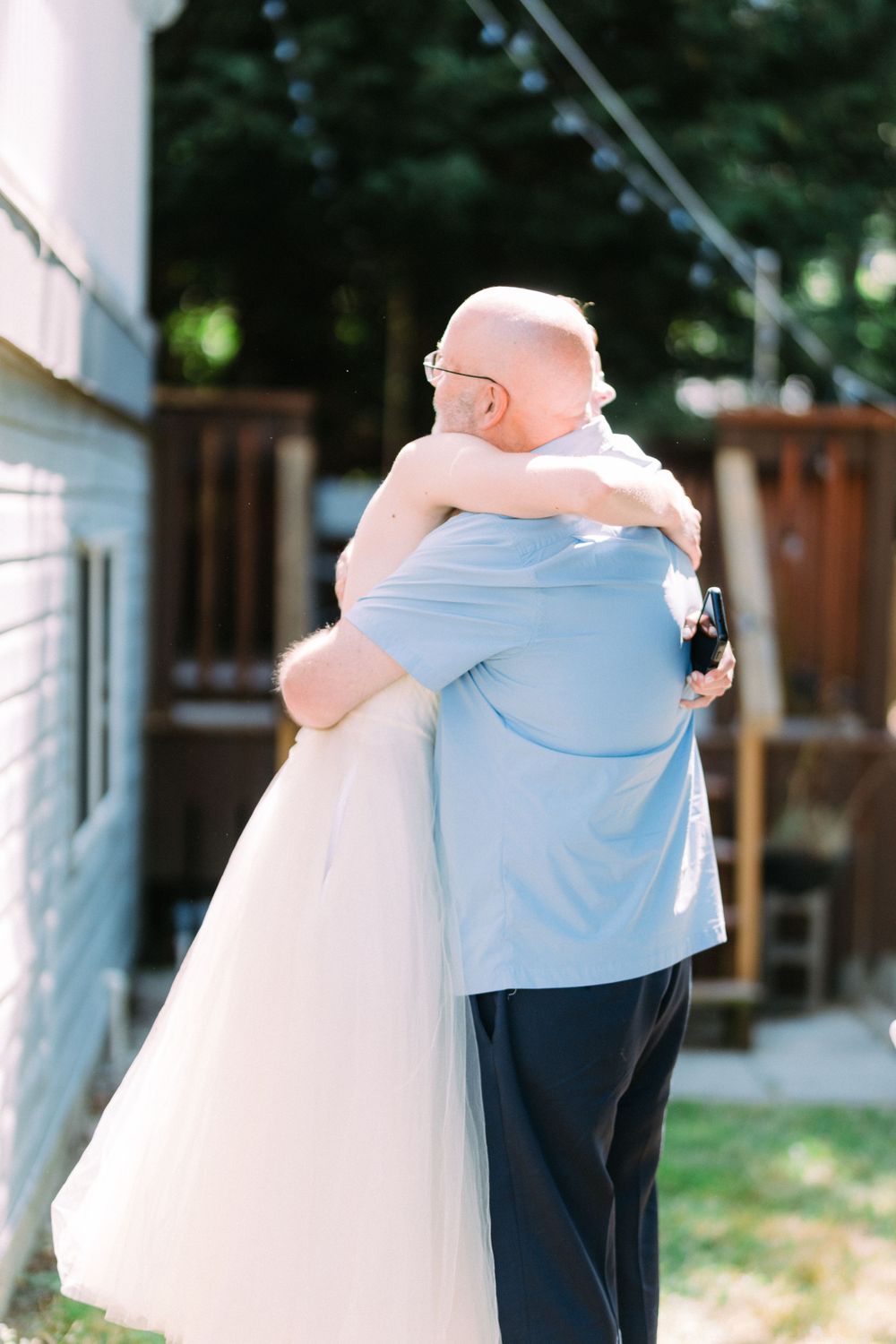 Two people sharing an emotional embrace at an outdoor wedding celebration.