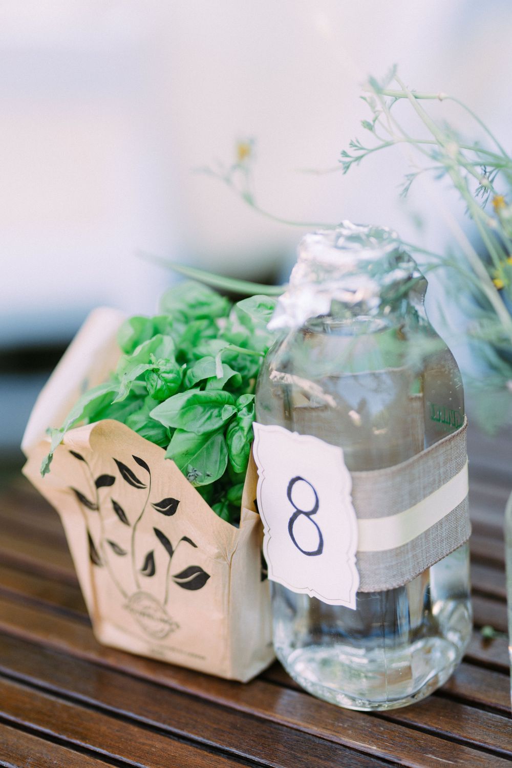 Wedding reception table decor with a rustic paper bag centerpiece and mason jar labeled with number 8.