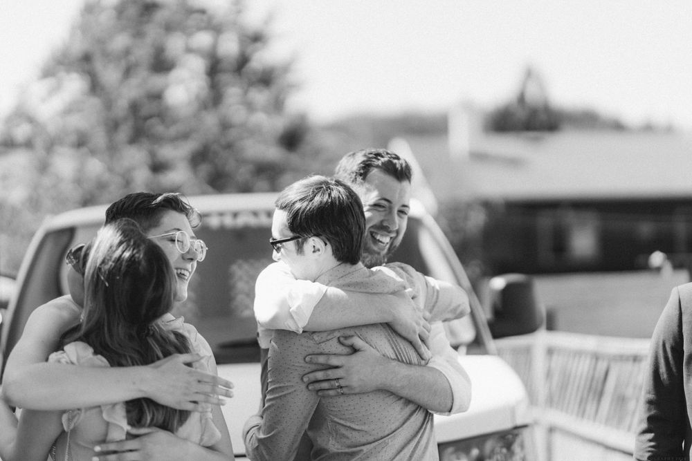 Black and white photo of people sharing emotional embraces at an outdoor gathering.