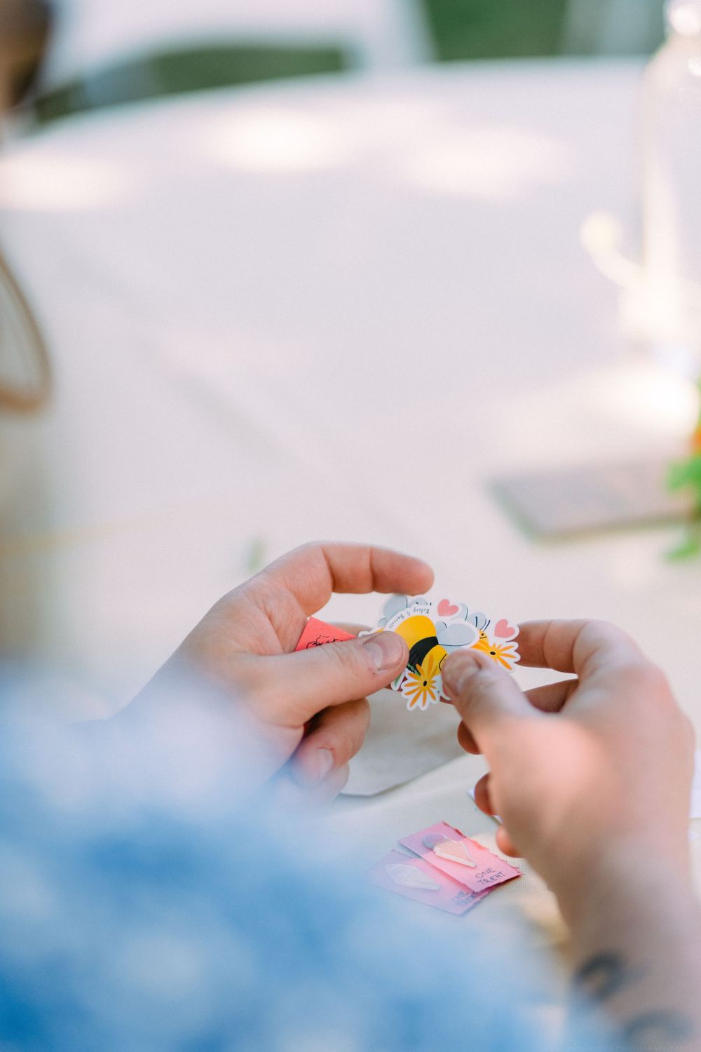 Close-up of hands holding a small decorative pin or badge.