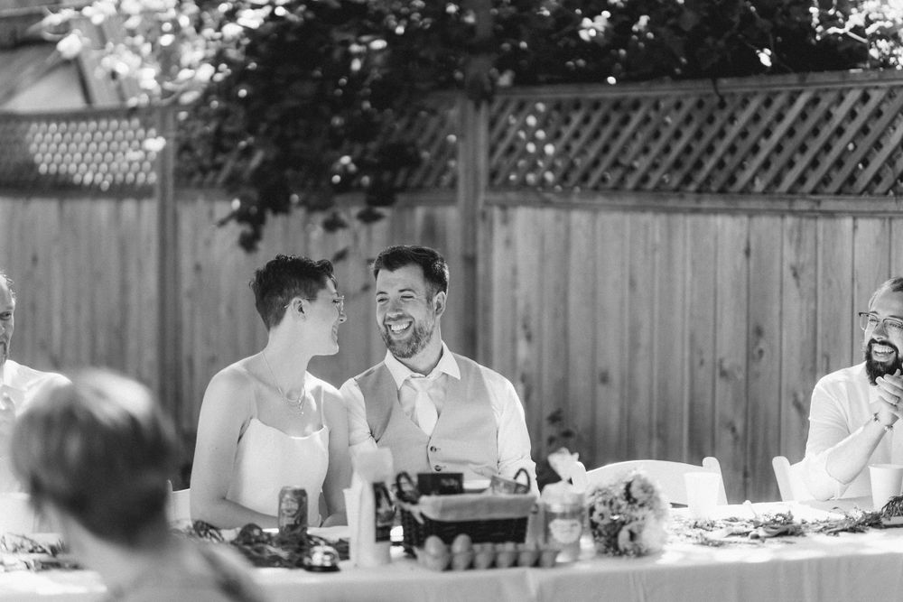 Guests engaged in lively conversation around a table at an outdoor garden party.