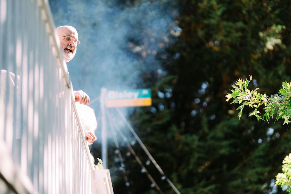 Smoke drifts past a white fence at an outdoor gathering.