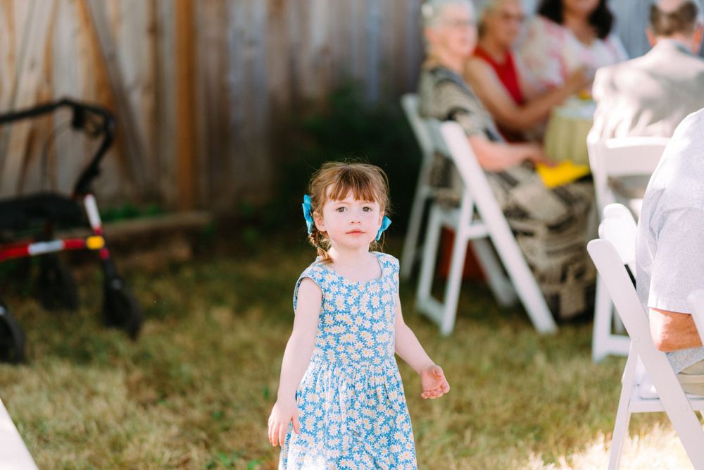 A small child in a blue polka dot dress exploring an outdoor party setting.