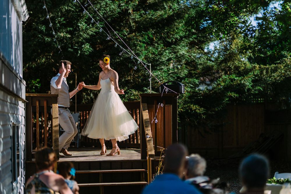 A couple dances on wooden steps during their outdoor summer wedding celebration.