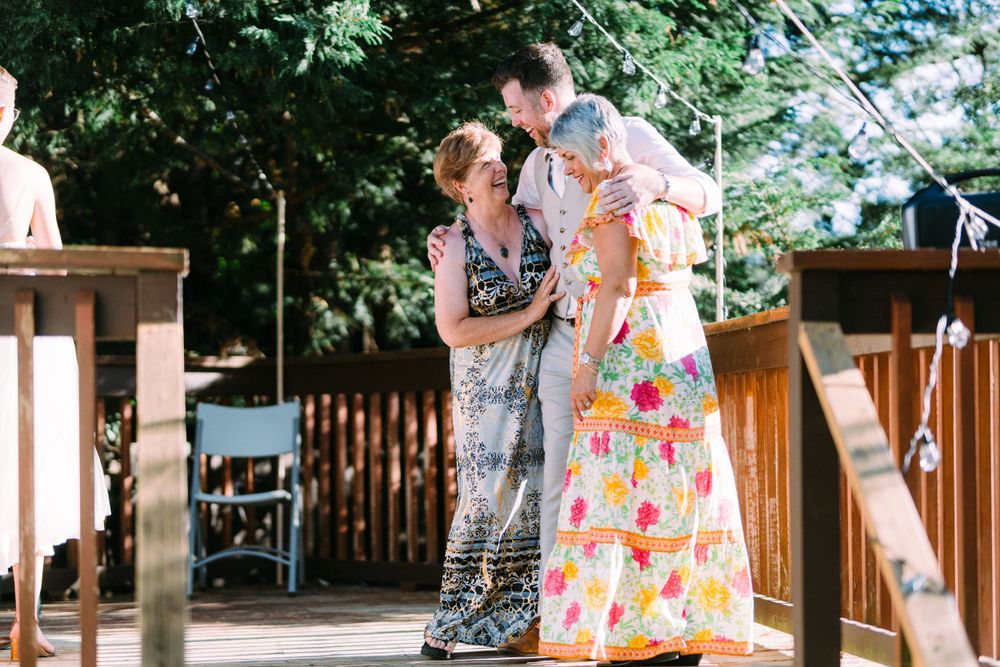 Colorful summer dresses stand out against wooden deck railings at an outdoor gathering.