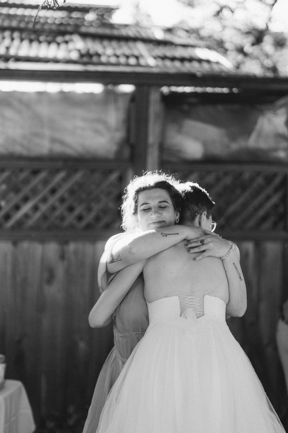 A black and white photo captures an emotional embrace in a white wedding dress.