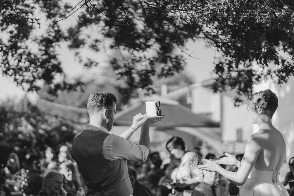 Black and white photo of guests raising glasses in a toast during an outdoor celebration.