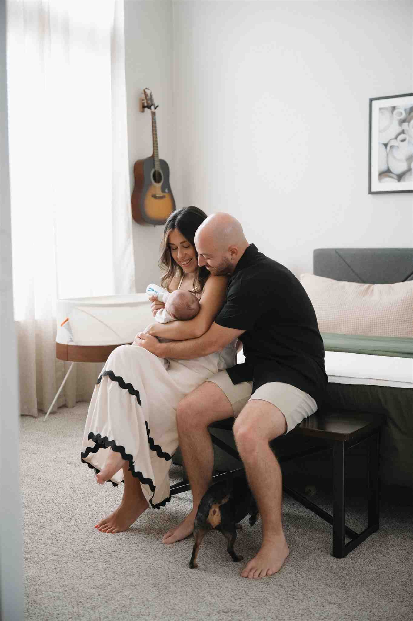 Two people sit together on a bench in a cozy room decorated with an acoustic guitar on the wall.