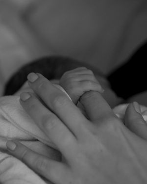 Newborn holding mother’s finger 24 hours after birth at Winchester Hospital, captured by a Boston newborn photographer