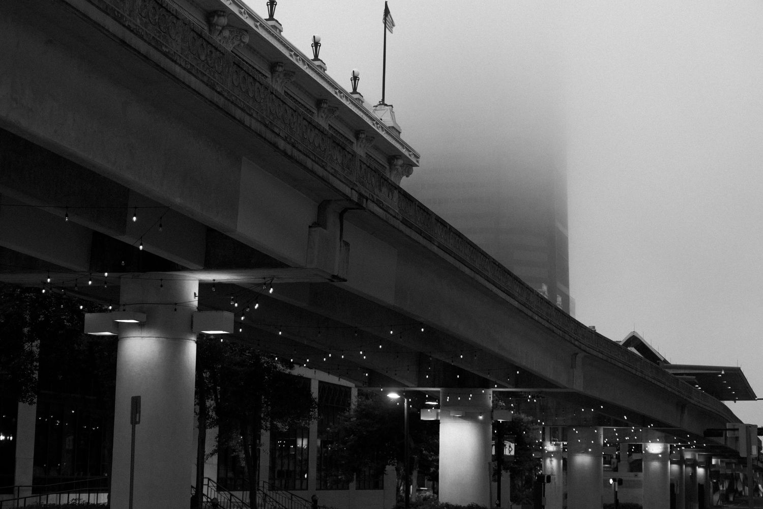 Modern urban architecture with illuminated columns and covered walkway in black and white.