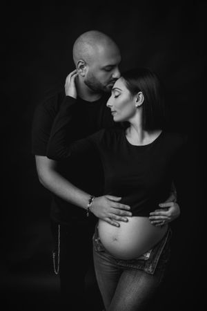 donna incinta abbraccia suo marito in posa