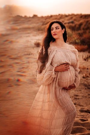 donna incinta in posa con il pancione al tramonto