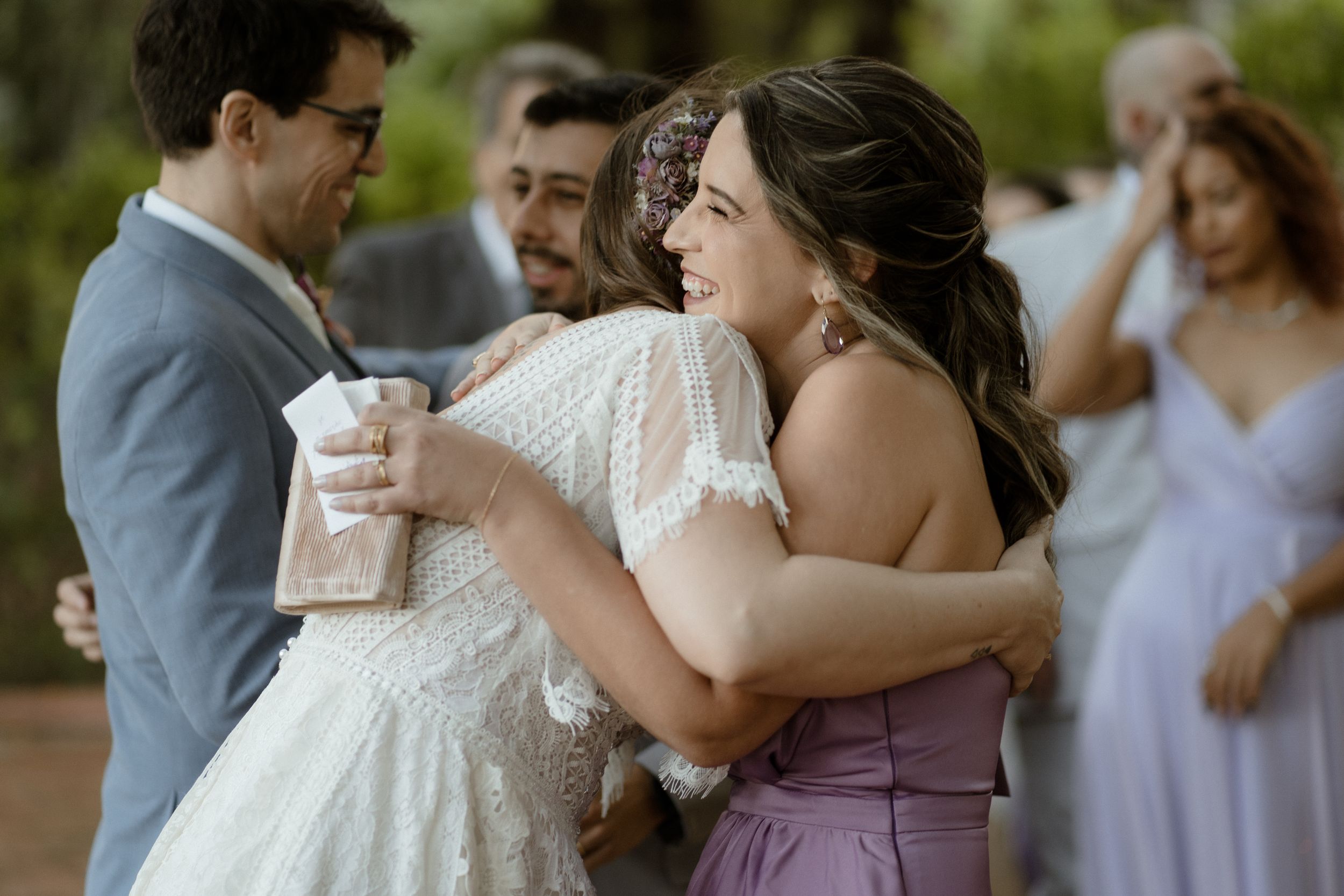 Wedding party embraces with joyful laughter during outdoor celebration.