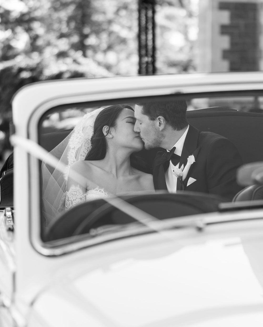 A romantic moment captured inside a classic white vintage car on a wedding day.