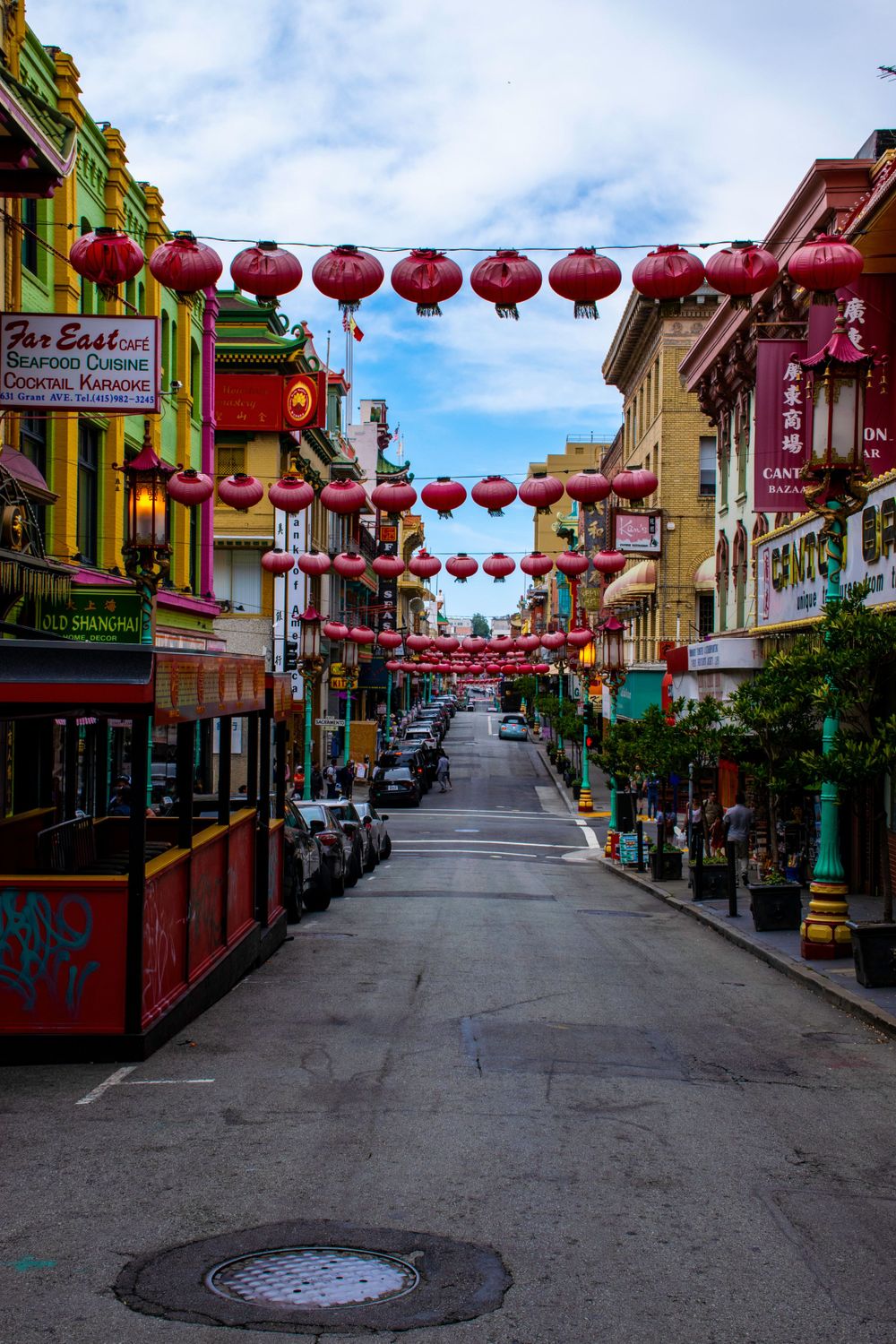 Red lanterns strung across a street in Chinatown with historic buildings and storefronts.