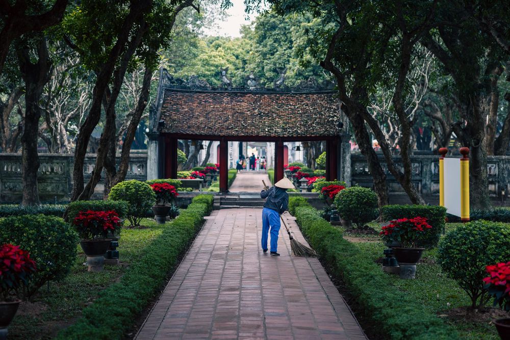 Tranquil garden pathway leading to traditional Asian temple with red decorations.