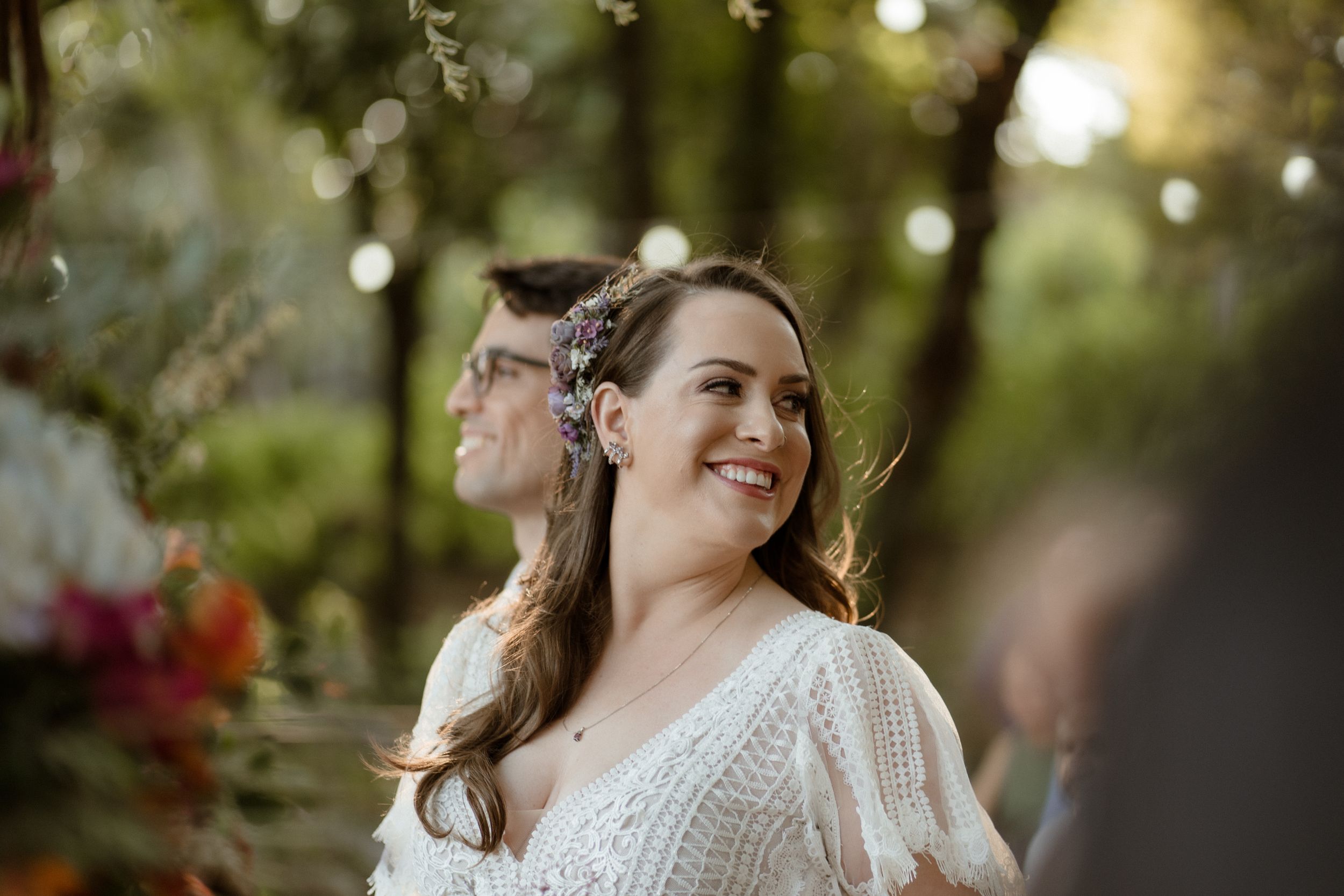 Lace wedding gown detail with beautiful natural lighting and bokeh in an outdoor garden setting.
