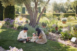 A tranquil garden scene shows someone tending to colorful flowers and plants in a lush outdoor setting.