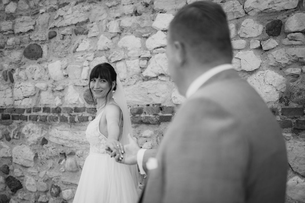 Black and white intimate moment between newlyweds against stone wall.