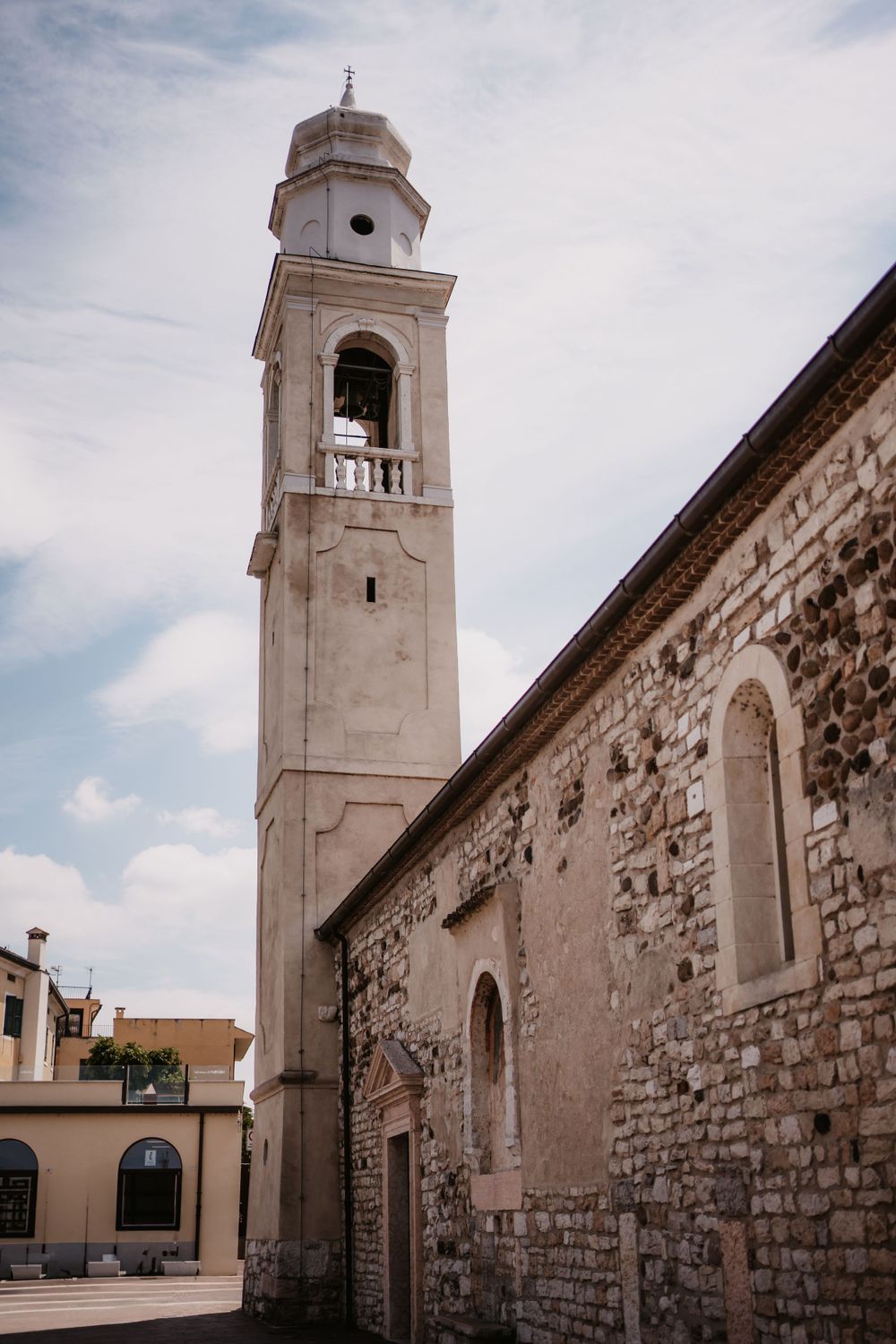 Tall stone bell tower of Mediterranean church against blue sky.