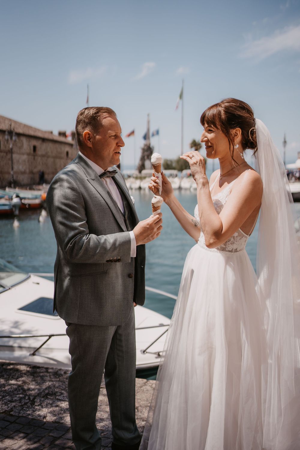 A couple shares ice cream cones at a Mediterranean marina on their wedding day.