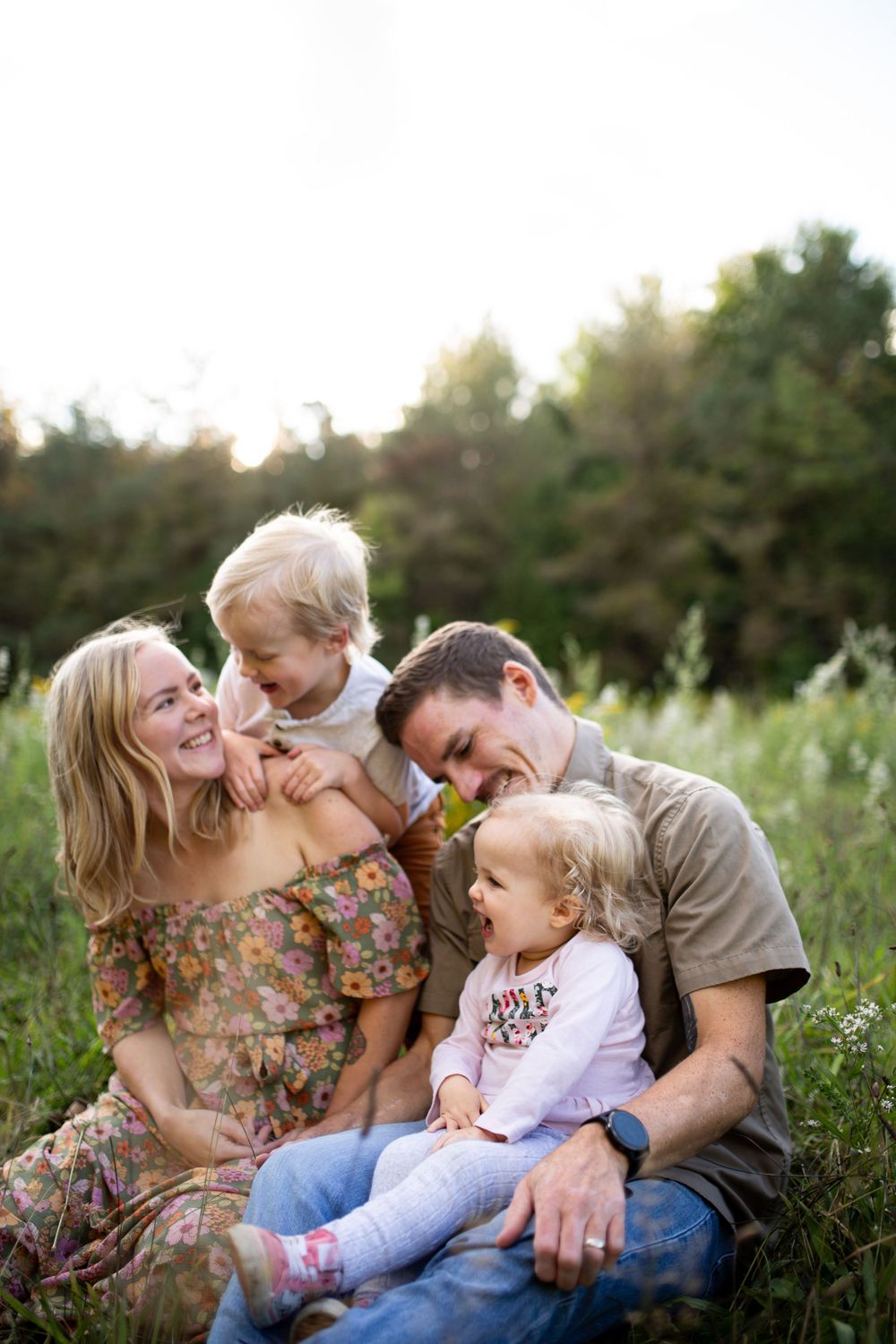 Family sharing joyful moments together while sitting in a wildflower meadow at sunset.