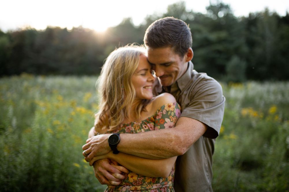 Romantic couple embracing in a wildflower field at sunset.