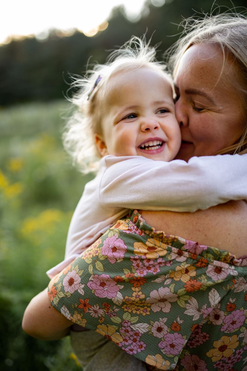 A tender moment shared between parent and child outdoors among wildflowers at sunset.