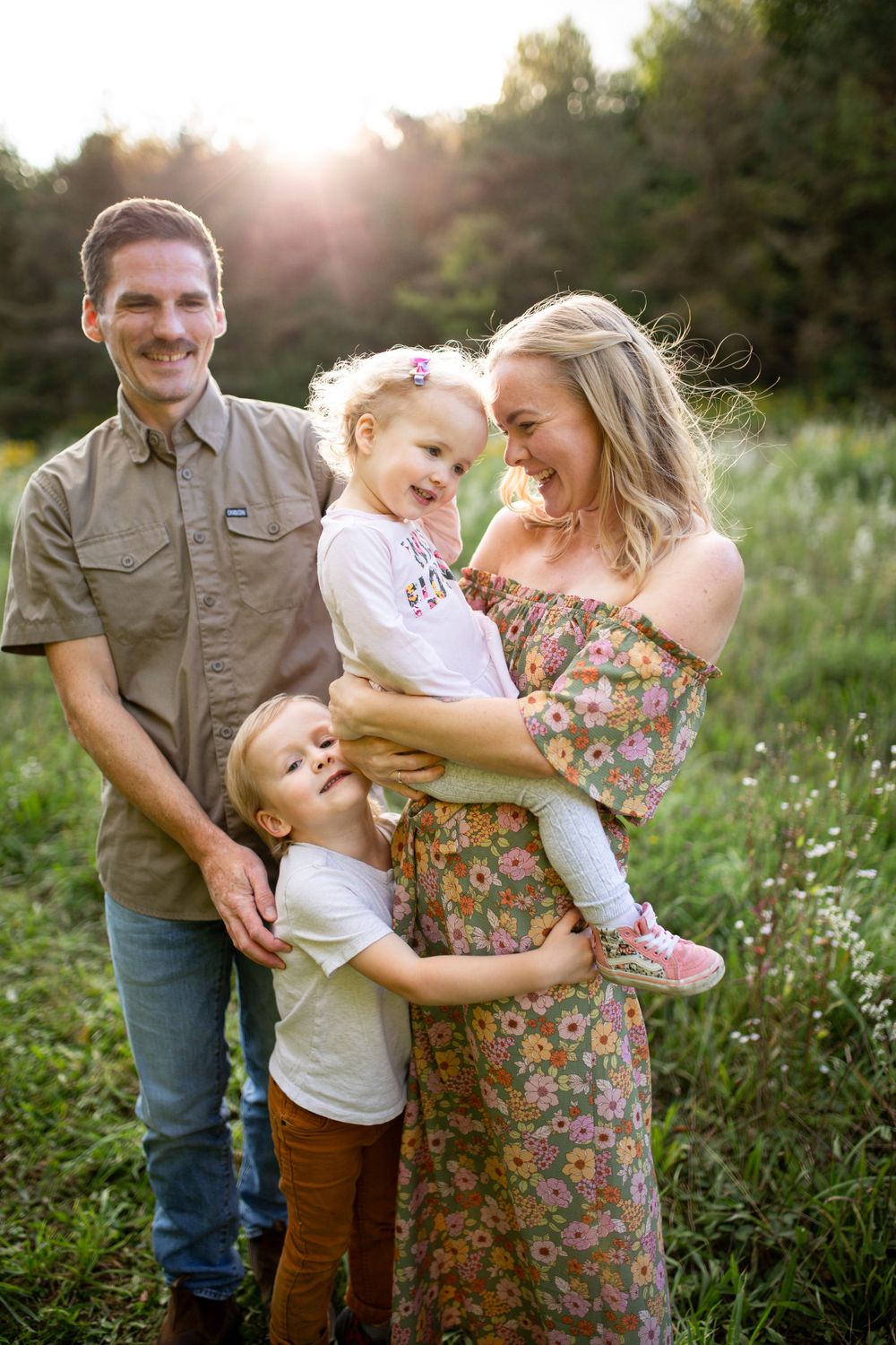 Happy family of four enjoying quality time together outdoors in a summer meadow.