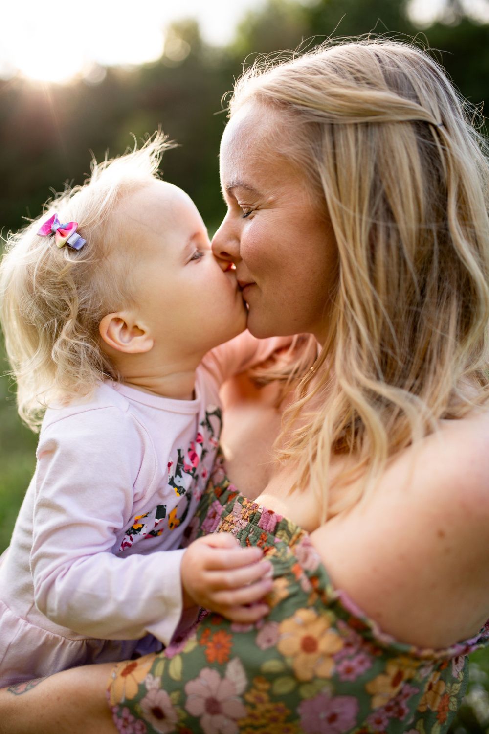 Intimate close-up of parent and child sharing an affectionate moment in golden sunlight.
