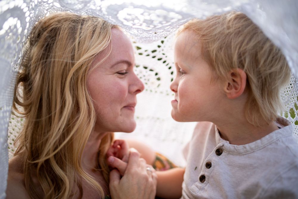Tender close-up moment between parent and child against white lace background.