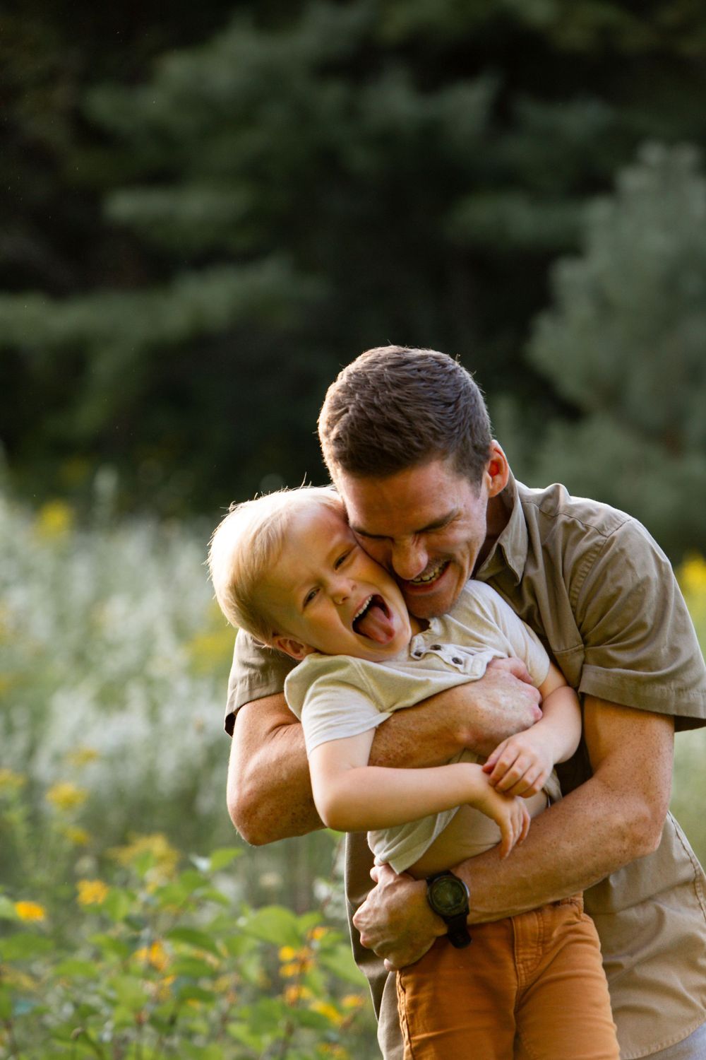 Playful embrace between parent and child in a field of yellow wildflowers.