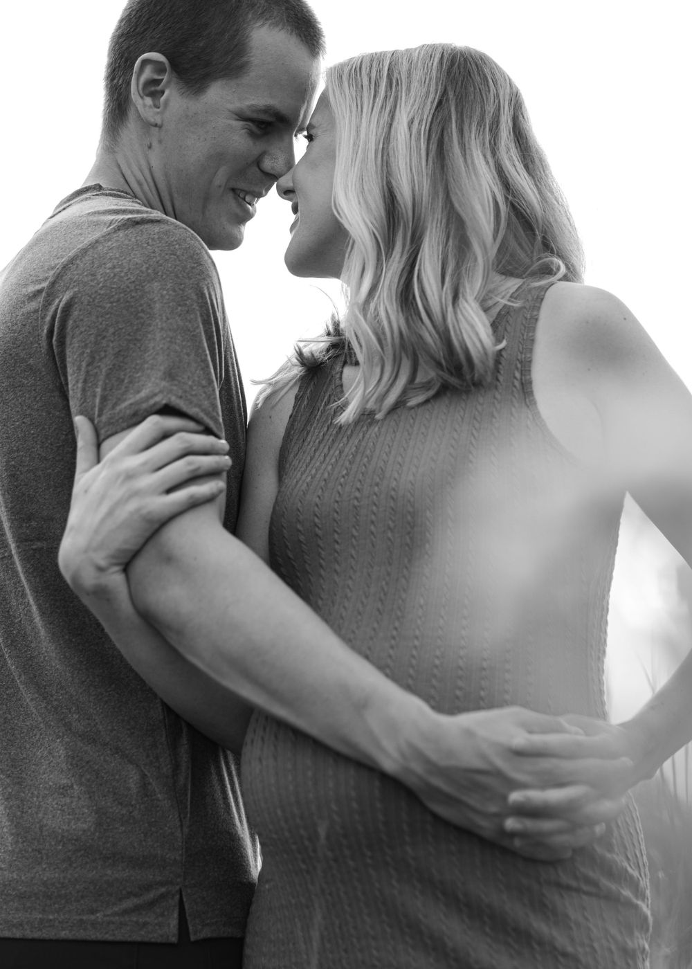 Black and white intimate portrait of couple sharing a tender moment outdoors.