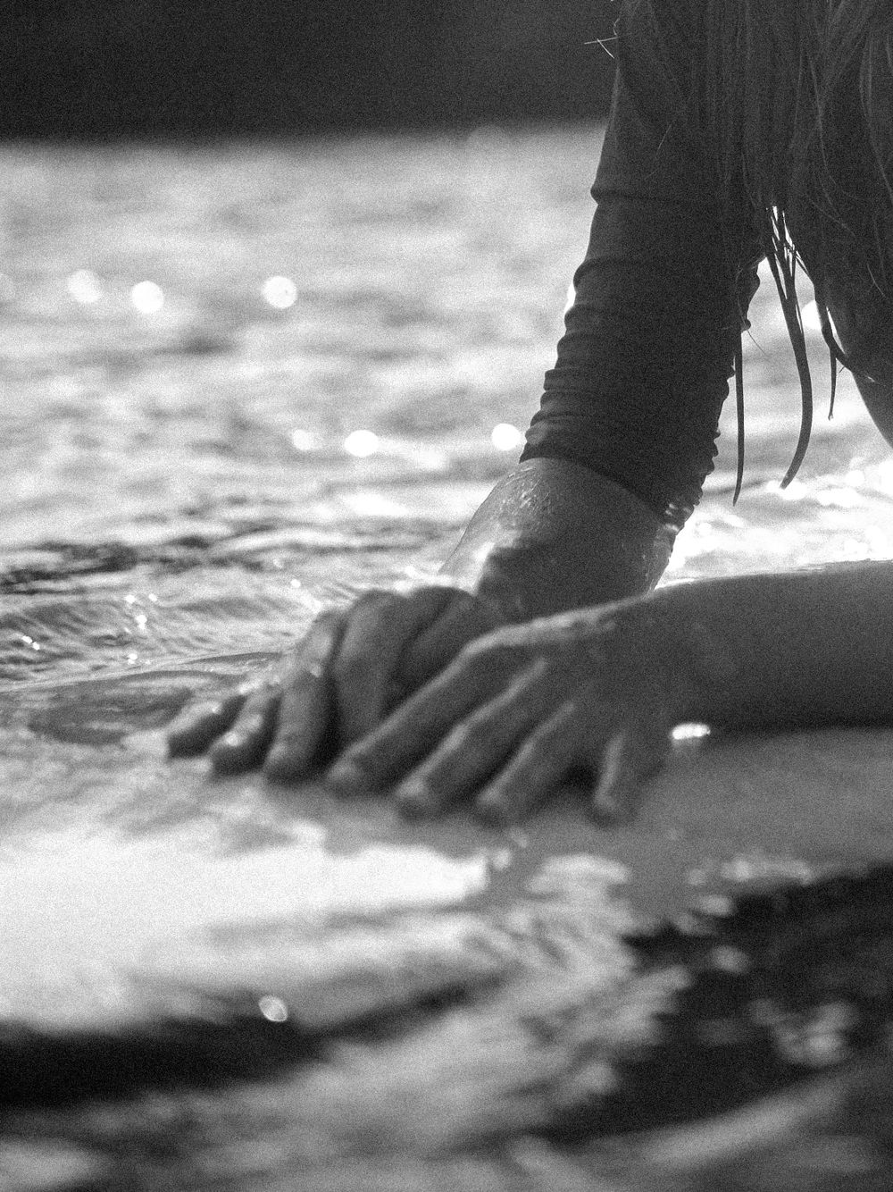 artsy detail picture of hands on the surfboard water photography black and white