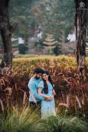 Romantic couple embracing in field of tall grass and trees during autumn.