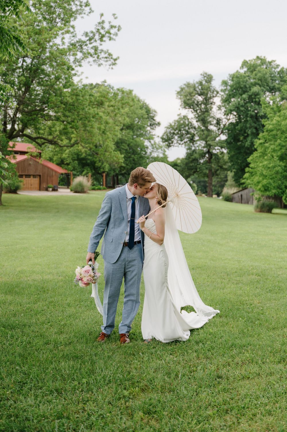 Couple kissing in green field on wedding day