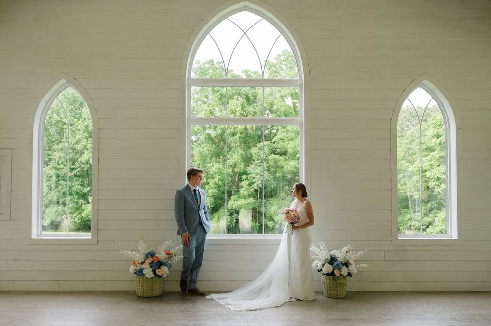 Bride and groom looking at each other in front of window