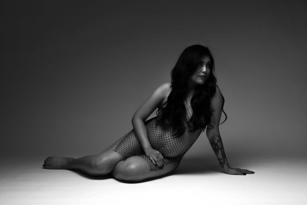 Artistic black and white boudoir photo on studio floor.