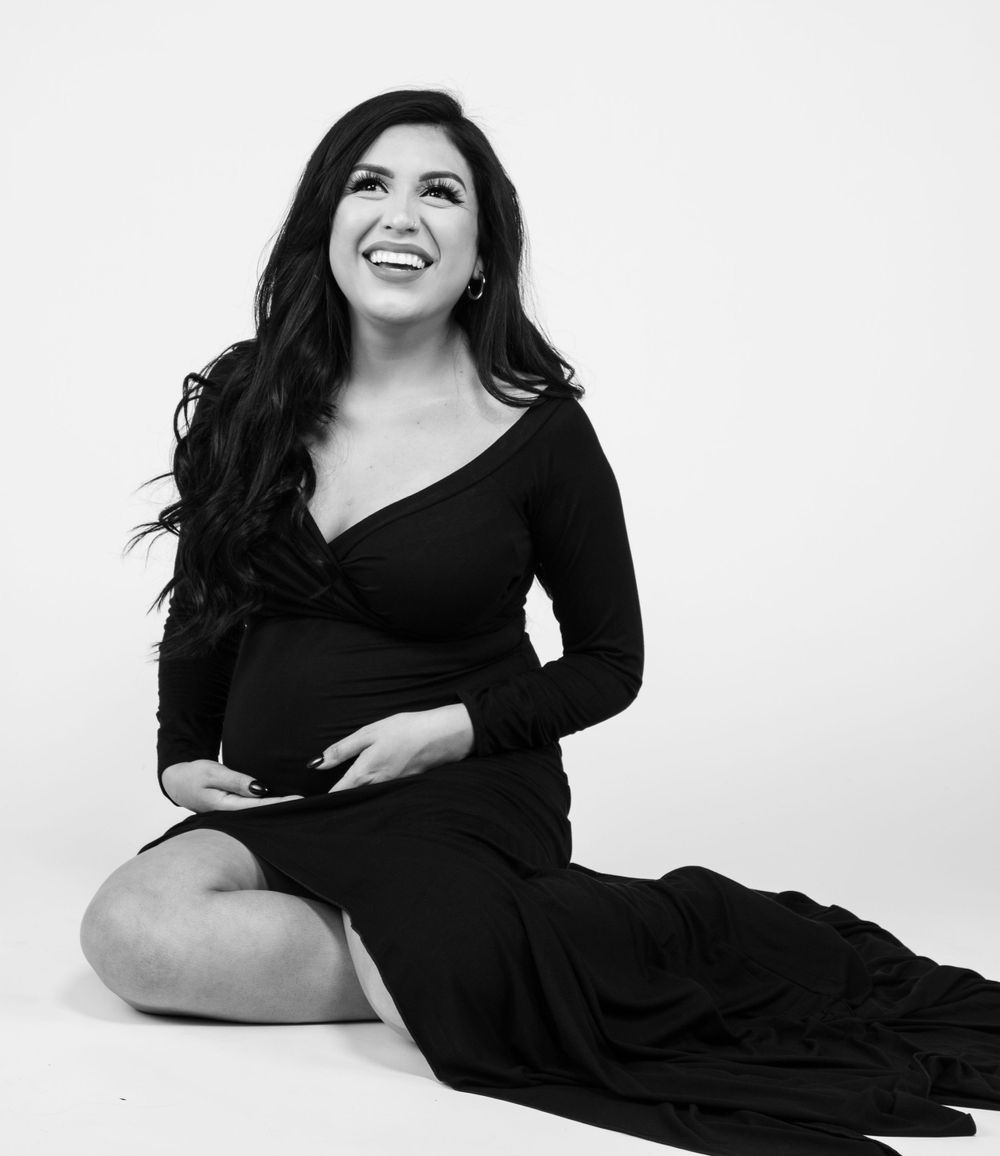 Black and white maternity portrait in long dress showing joyful expression.
