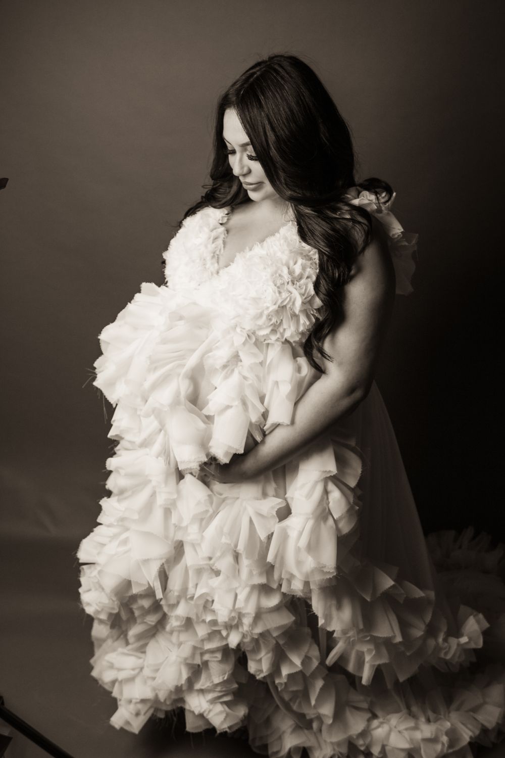 Dramatic black and white portrait in flowing ruffled white gown.