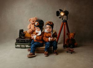 Vintage-inspired photo of a child with teddy bears and antique camera equipment in sepia tones.