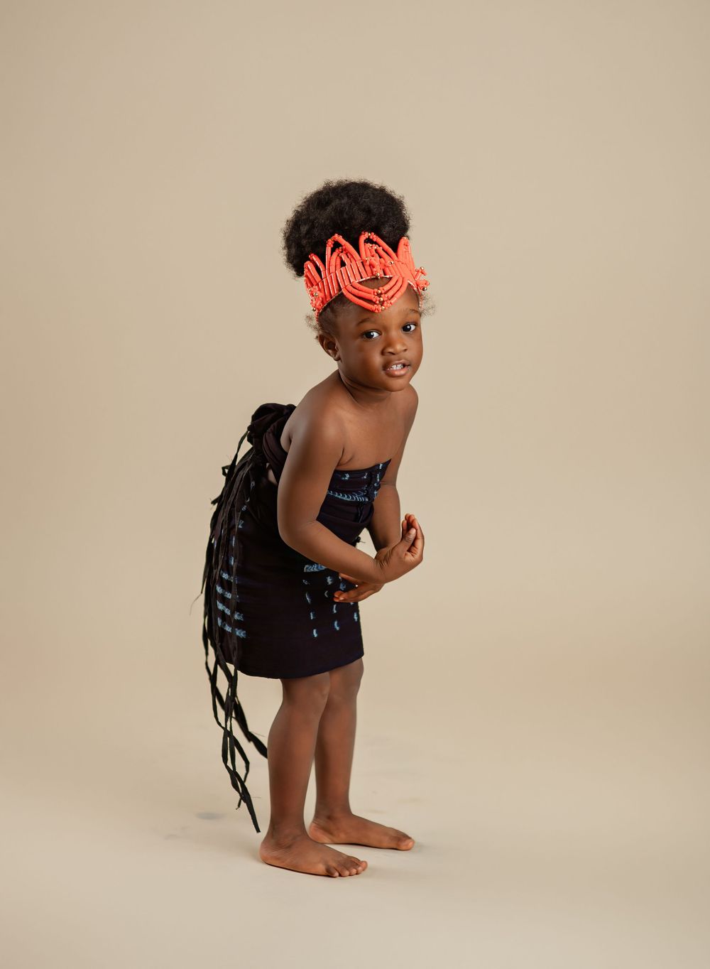 Playful studio portrait with neon accessories and black outfit against beige background.