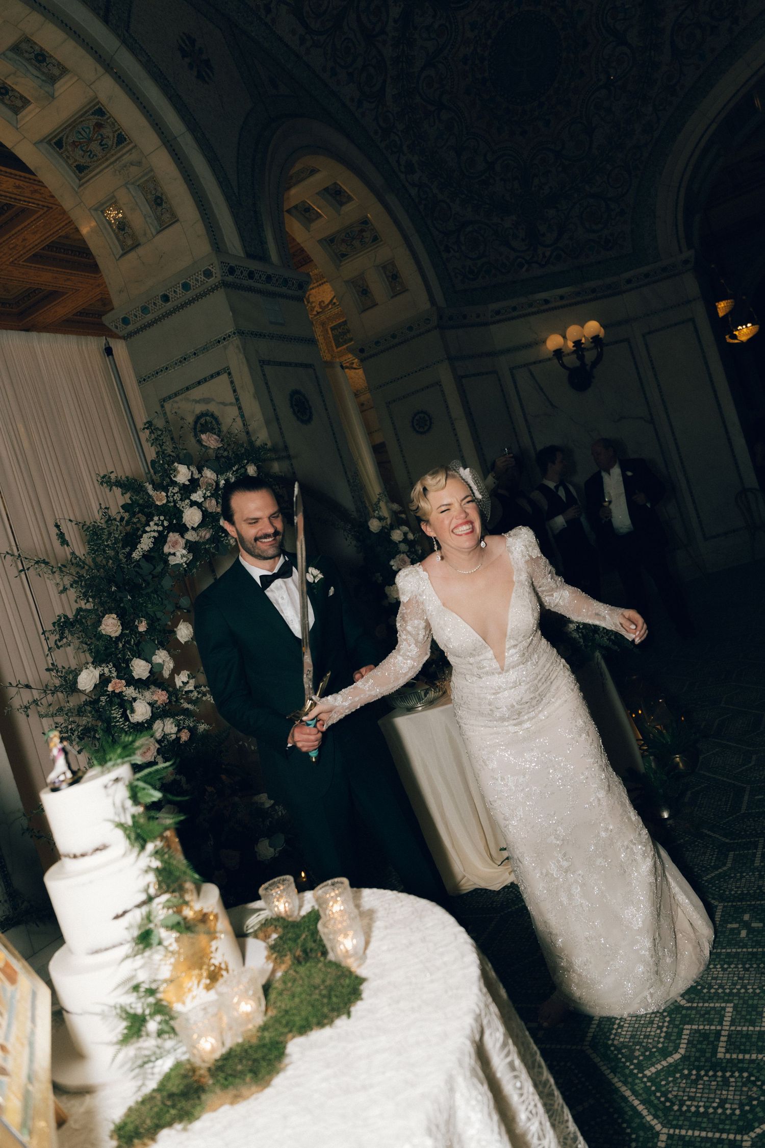 A white wedding dress hangs from a wooden pergola in a black and white photograph capturing bridal elegance.