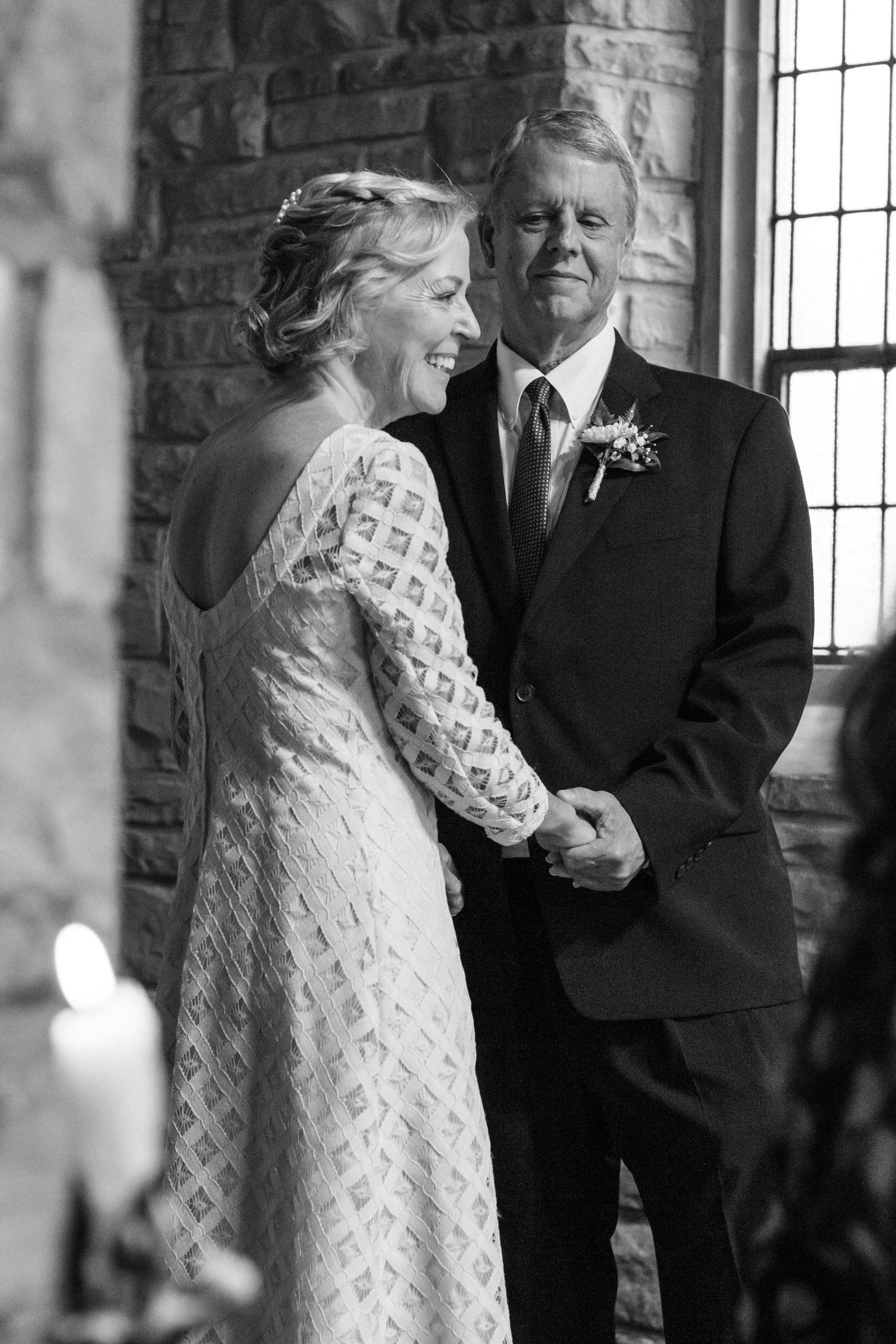 A joyful moment captured in black and white inside a brick-walled room with window light.