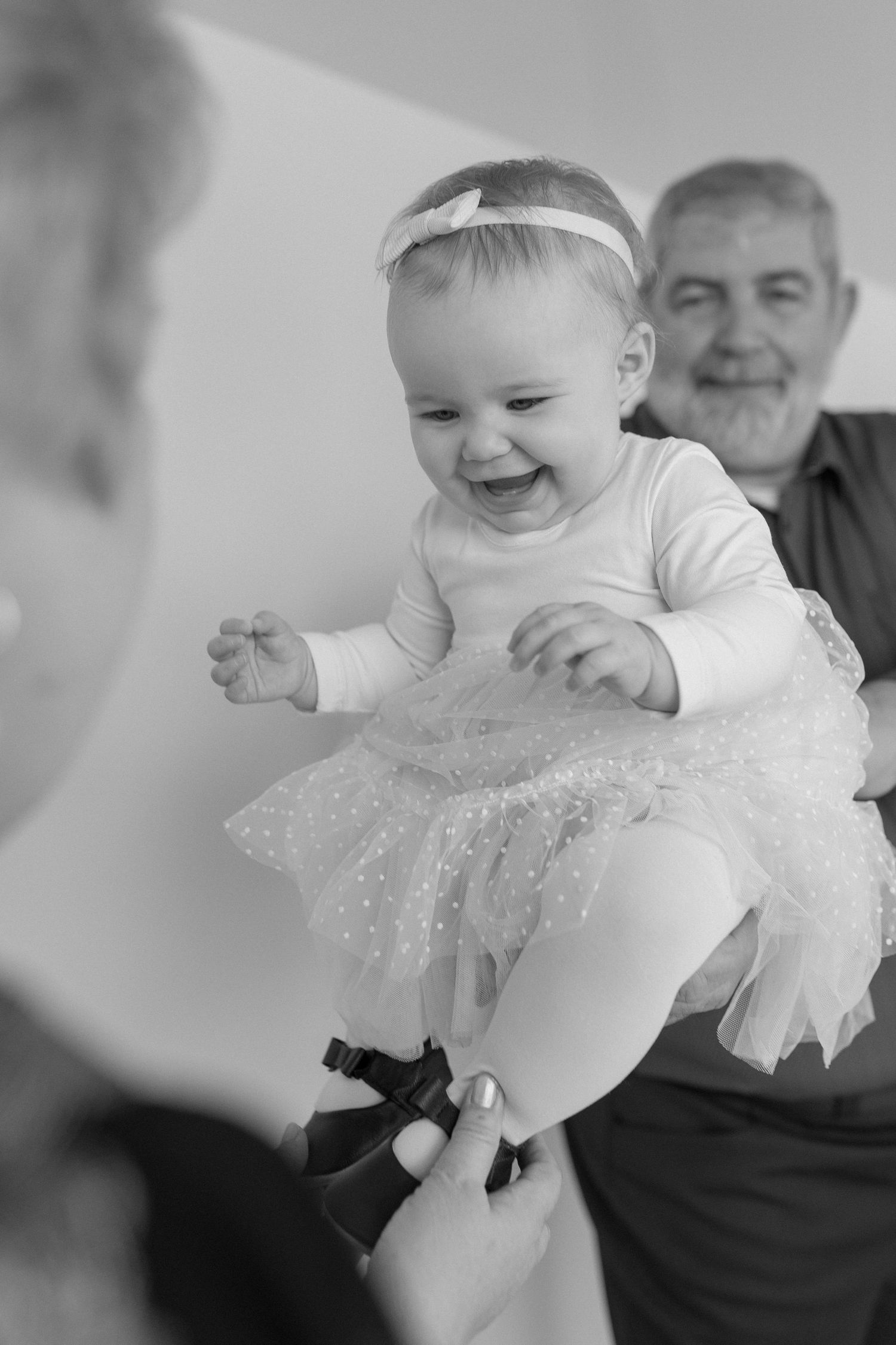 Black and white sequence of a laughing baby in a lace dress.