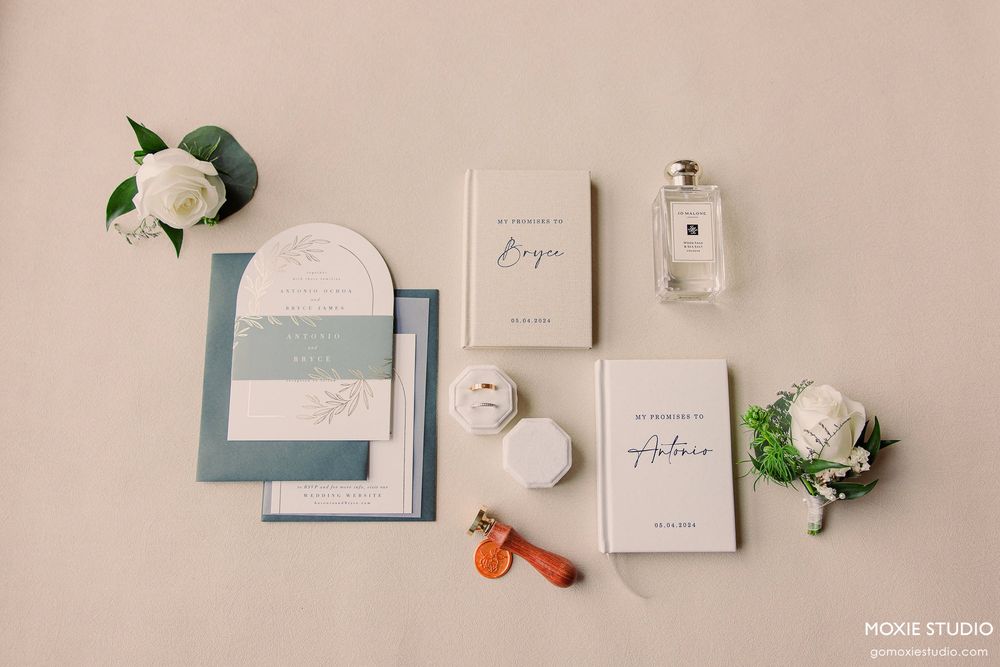 Elegant wedding stationery flatlay featuring soft blue and white invitations with floral accents and wax seals.