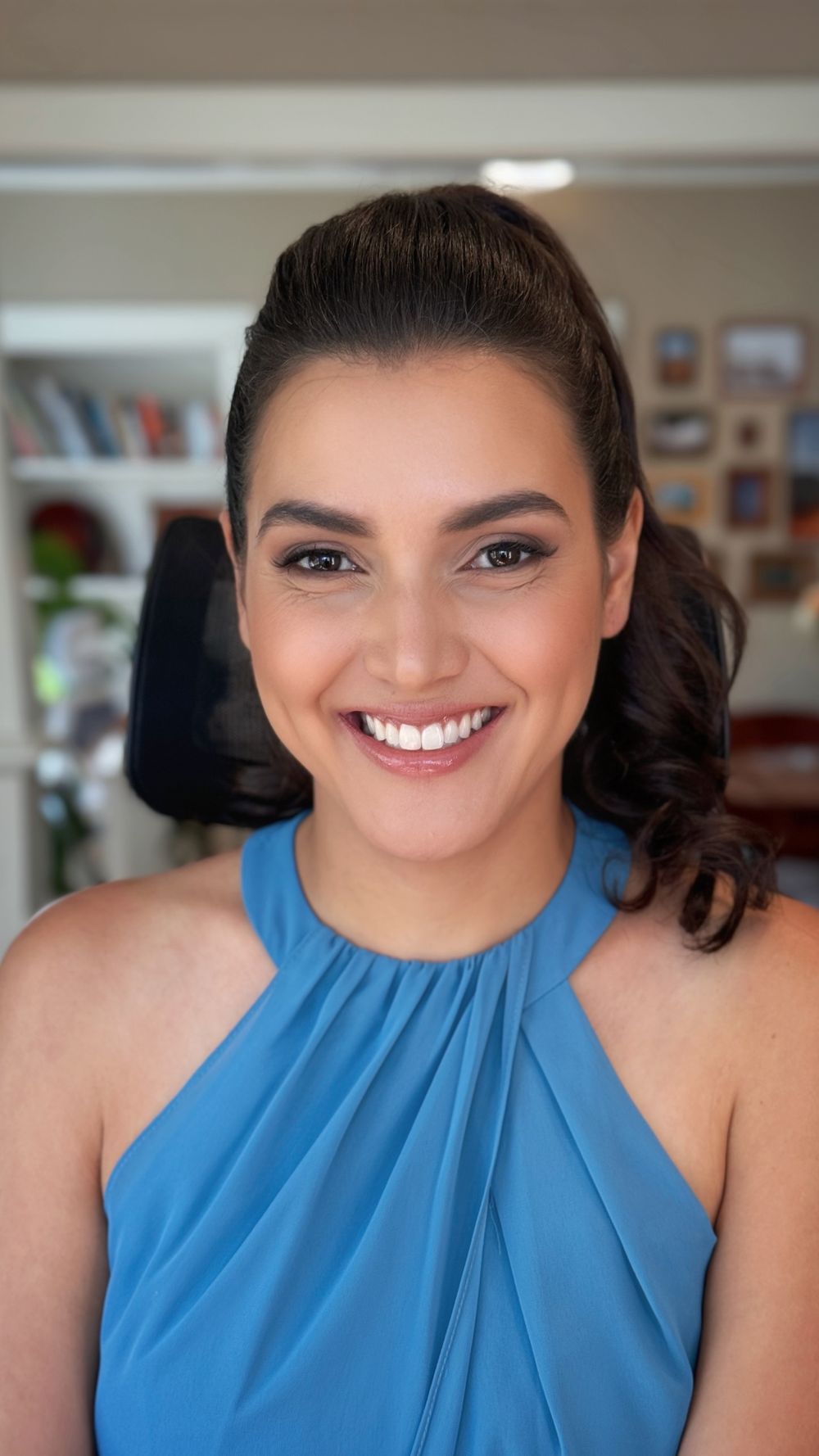 Portrait of someone wearing a pleated blue halter top with glamorous makeup.